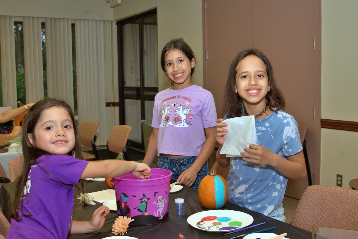 Three girls smile while painting