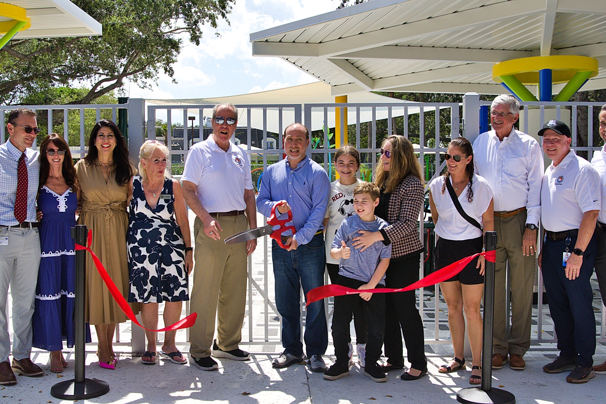 David Ogman, flanked by the Ogman family, District Commissioners and City of Boca Raton officials, cuts the ceremonial ribbon to open Patch Reef Park's new all-inclusive playground.