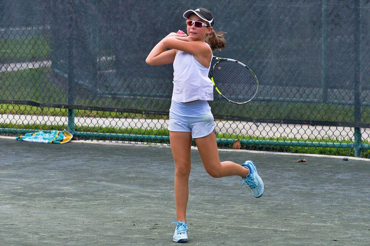 Junior Tennis girls participant hits her shot