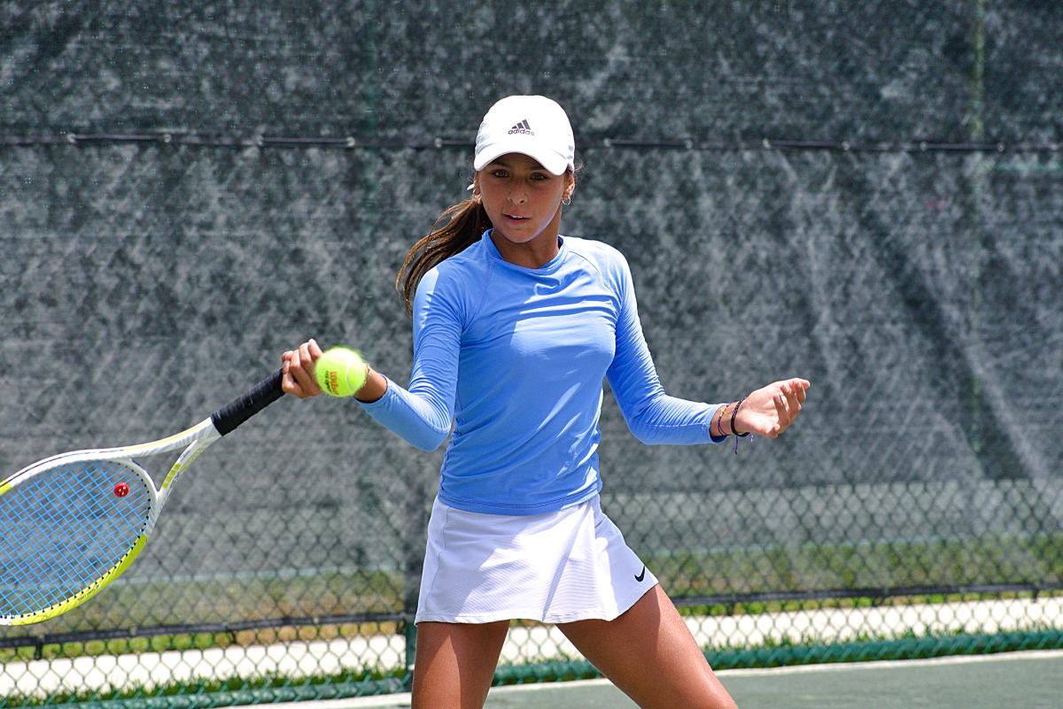 Junior Tennis girls participant begins her swing