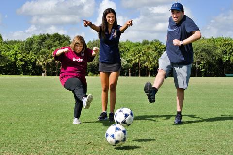 Claire McDonough shows buddies Sally Bahn and Matthew Lesser where to kick the ball.